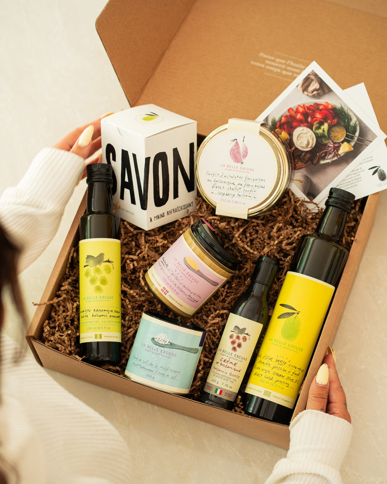 La Belle Excuse Signature Gift Box featuring green extra virgin olive oil, white balsamic vinegar, balsamic glaze, French shallot confit, roasted garlic mustard, Mediterranean fleur de sel, and refreshing hand soap.
