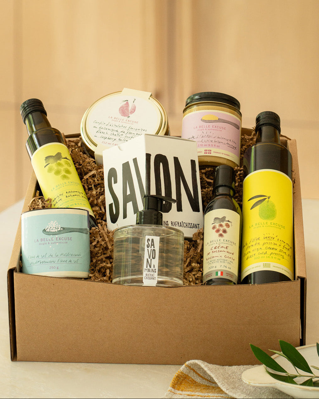 La Belle Excuse Signature Gift Box featuring green extra virgin olive oil, white balsamic vinegar, balsamic glaze, French shallot confit, roasted garlic mustard, Mediterranean fleur de sel, and refreshing hand soap.
